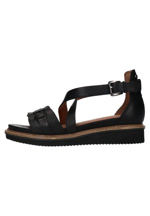 Sandale femme en cuir noir avec bride cheville, fermeture à boucle, semelle compensée basse et semelle extérieure en caoutchouc texturé.