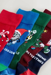 Multifarvede strømper: røde med candy cane, blå med nisse, grøn med juletræ og kastanjefarvede med trykt tekst. Strikket tekstur, ribbede manchetter.