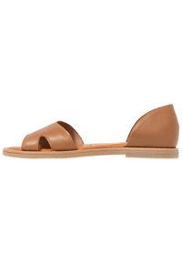 Sandalias de cuero marrón con suela plana, diseño de punta abierta y tacón redondeado. Textura suave con costuras mínimas y sin herrajes visibles.