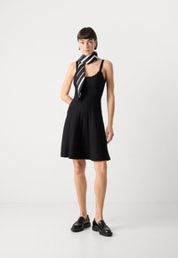 Mustat ribbed-mekko, jossa on hyvin istuva yläosa ja levenevä hame. Ominaisuuksina on aaltoileva pääntie ja ohuet hihnat. Yhdistetty musta-valkoiseen raidalliseen huiviin.
