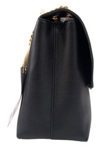 Borsa a tracolla nera in pelle con forma strutturata, dotata di una catena dorata. Texture liscia e design minimalista. Etichetta attaccata.