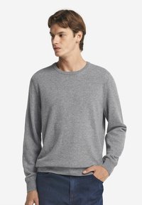 Hellgrauer Rundhals-Pullover, lange Ärmel, gerippte Bündchen und Saum, weiche Textur, kombiniert mit navyblauen Hosen, schlichtes und klassisches Design.