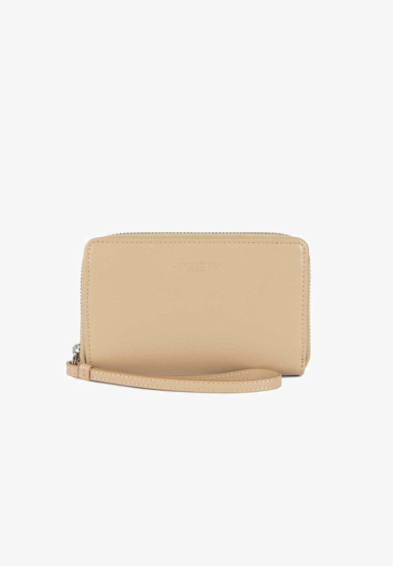 Portafoglio in pelle beige con chiusura a zip, fascia da polso e logo "LANCASTER" impresso sul davanti. Texture liscia, forma rettangolare.