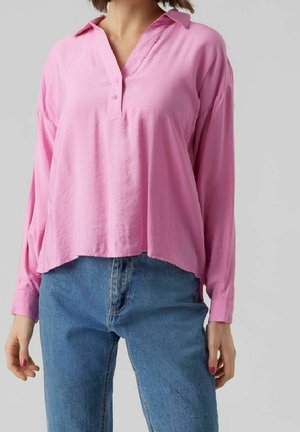 Rosa langärmlige Bluse mit V-Ausschnitt und Knopfdetails, aus leichtem Stoff, kombiniert mit hochtaillierten blauen Jeans.