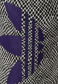 Svart och vit texturerad tyg med ett ormskinnsmönster, med en framträdande lila design med geometriska former och ränder.