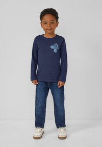 Granatowa koszulka z długim rękawem z jasnoniebieskim wzorem; w połączeniu z niebieskimi dżinsami i białymi trampkami; luźny krój i miękki materiał bawełniany.