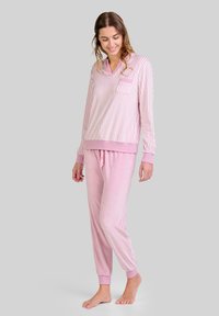 Conjunto de pijama rosa que incluye una parte superior de rayas de manga larga con escote en V y un bolsillo en el pecho, combinada con pantalones tapered rosa claro lisos.