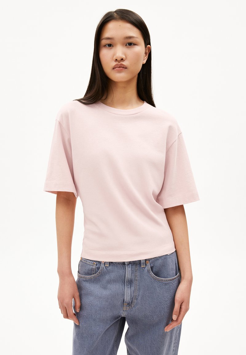 Helles rosa Oversized-T-Shirt mit kurzen Ärmeln, Rundhalsausschnitt, aus weichem Baumwollmaterial, kombiniert mit lockeren blauen Jeans.