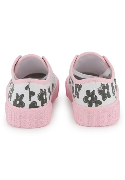 Πάνινα παπούτσια με λευκή βάση και μαύρο λουλουδένιο σχέδιο. Οι καουτσούκ σόλες είναι ροζ με υφή. Εικόνα από πίσω πλευρά.