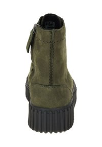 Bottines en suède vert avec une fermeture éclair à l'arrière, semelle noire texturée et design à bout rond. Coutures visibles sur le dessus.