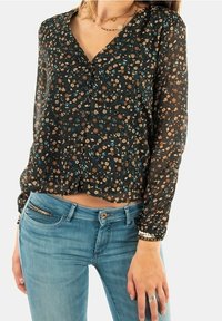 Black floral blouse with long sleeves, a V-neckline, and button closure. Features small floral patterns in brown and blue on a sheer fabric.