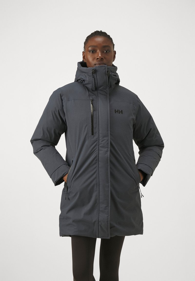 Tmavě šedá izolovaná parka s vysokým límcem, kapsami na zip a detailem loga. Disponuje elegantním designem a odolnou tkaninou.