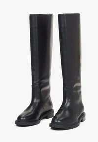 Pár vysokých �černých kožených bot s nízkým blokovým podpatkem a zaoblenou špičkou, stojící vzpřímeně na bílém pozadí.