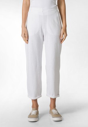 Pantaloni bianchi in lino con una vestibilità rilassata, dotati di tasche anteriori e orli arrotolati. Tessuto morbido e leggero, abbinati a scarpe in tela.