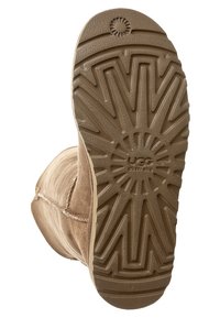 Brązowy zamszowy but z teksturowaną gumową podeszwą z wzorem rozbłysku gwiazdy i wytłoczonym logo marki. Widoczny detal szwu bocznego.