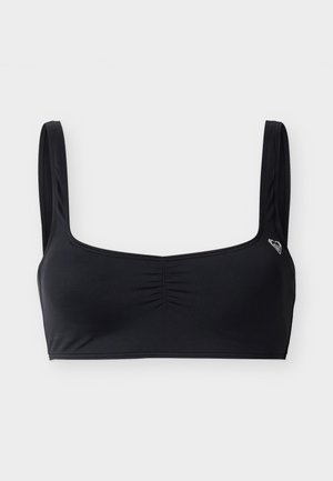Μαύρο αθλητικό σουτιέν με φαρδιούς ιμάντες στους ώμους και ελαφρύ ρίξιμο στο κέντρο μπροστά, παρουσιάζεται σε απλό ανοιχτό φόντο.
