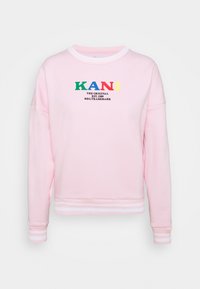 Sudadera rosa con cuello y puños acanalados. Presenta un logo multicolor "KANI" sobre "THE ORIGINAL EST. 1989" en negro.