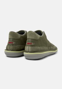 Grüne Wildlederschuhe mit Netzdetails, einer Gummisohle und einer grauen Außensohle. Mit einem roten "Camper"-Logo an der Ferse. Niedriges Profil-Design.