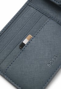 Skórzany, ciemnoniebieski etui na karty z trzema przegródkami, o fakturowanej powierzchni i ozdobnym paskiem z nici złotych, białych i czarnych. Wytłoczony logo BOSS.