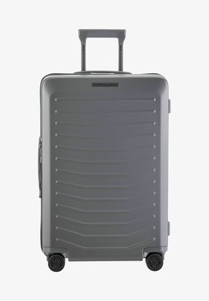 Maleta rígida gris con una superficie texturizada y estriada, mango telescópico y cuatro ruedas negras. Cuenta con cierre de cremallera.