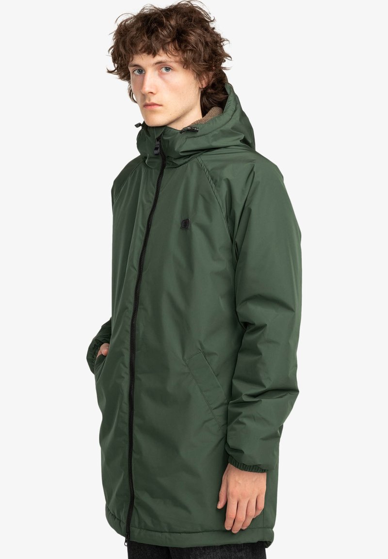 Parka impermeabile verde con zip frontale, cappuccio e tasche laterali. Presenta una fodera morbida e texturizzata e polsini elastici.