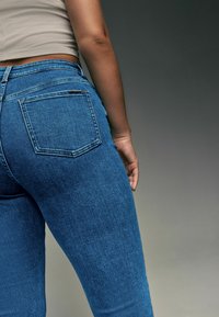 Blauwe spijkerbroek met een getailleerd ontwerp, hoge taille en achterzakken. De stof is textuurvol met een lichte rek voor extra comfort.