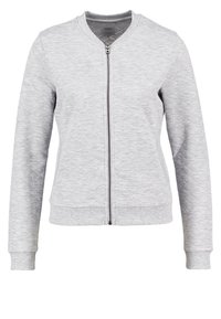 Ljusgrå kviltad zip-up jacka med ribbade manschetter och nederkant, utan krage, och långa ärmar.