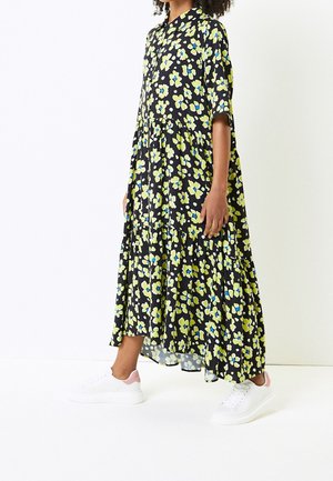 Kwiatowa sukienka na czarnym tle, z jas зеленymi i niebieskimi kwiatami, warstwowa konstrukcja i krótkie rękawy, w połączeniu z białymi trampkami.