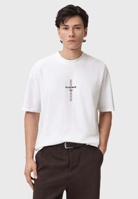 Valkoinen puuvillapaita, jossa on pyöreä kaula-aukko, keskellä musta ja purppura "ALLSAINTS" -graafinen kuvio. Löysä malli, lyhyet hihat.