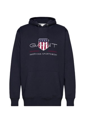 Mornarji modra kapuca z vrvico, sprednji žep in izšit logotip s ščitom v rdeči in beli barvi ter besedo "GANT".