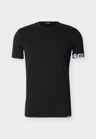 T-shirt noir à manches courtes et col rond avec un texte blanc partiel sur la manche droite et une petite étiquette logo sur l'ourlet inférieur.