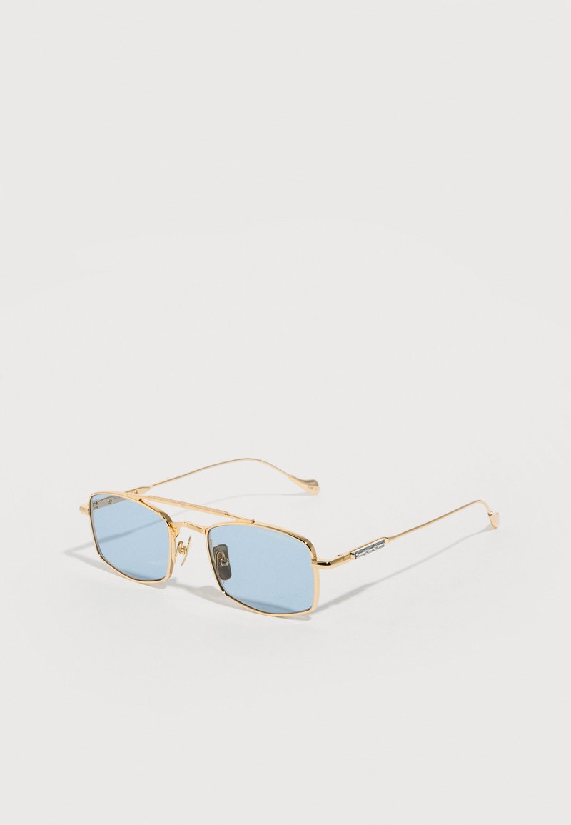 Gold-framed rectangular sunglasses with light blue tinted lenses and thin metal temples, resting on a light surface.