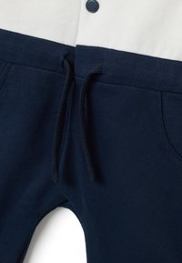 Pantalones de chándal azul marino con cintura elástica y cordón, que cuentan con bolsillos laterales y una tela suave y texturizada.
