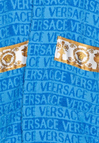 Modrá texturovaná tkanina s reliéfním logem "VERSACE" a zlatými akcenty s dekorativními vzory, včetně motivu medúzy.