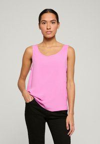 Roze mouwloze top met een ronde halslijn, gemaakt van een gladdige stof. Ontworpen met een casual pasvorm, met een subtiele drapering en zijsplitten.