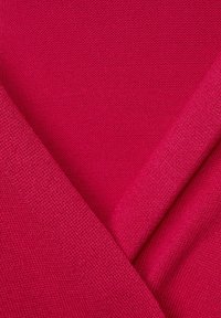 Fuchsia stickad tyg med en mjuk textur, med överlappande sektioner och en lätt, andningsbar design.