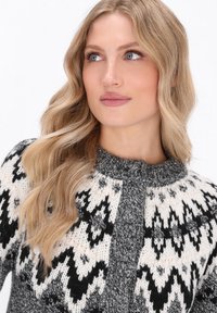 Strickpullover mit einem Muster aus schwarzen und cremefarbenen Zickzacklinien, einem grauen strukturierten Einsatz und einem gerippten Kragen.