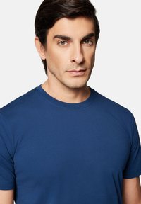 Granatowa koszulka z krótkim rękawem wykonana z gładkiego materiału, z okrągłym dekoltem, dopasowanym krojem i minimalnymi detalami szwów.