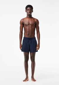 Himmelblaue Badeshorts aus leichtem Stoff mit elastischem Bund und Kordelzug, die ein einfaches, unauffälliges Design aufweisen.