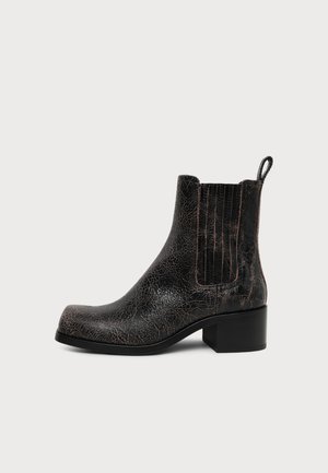 Bottine noire en cuir avec panneau latéral élastique, bout carré, talon bloc et languette à l'arrière, présentée sur fond blanc.