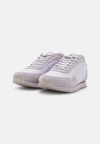 Lila sneakers med en blandning av mocka och släta material, med en texturerad sula och kontrasterande accenter, designade för komfort och stil.