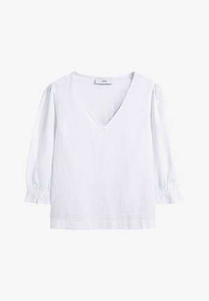 Blouse blanche avec col en V, manches longues bouffantes et poignets à volants élastiqués, confectionnée en tissu texturé léger.