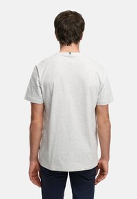 Grå t-skjorte med kort erme og rund hals, laget av mykt stoff. Har et lite logomerke nær nakken bak. Ledig passform.