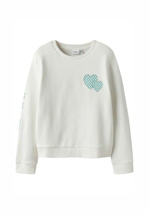 Sweatshirt blanc à manches longues avec un col rond, présentant deux petits cœurs à carreaux verts et blancs sur le haut gauche de la poitrine.