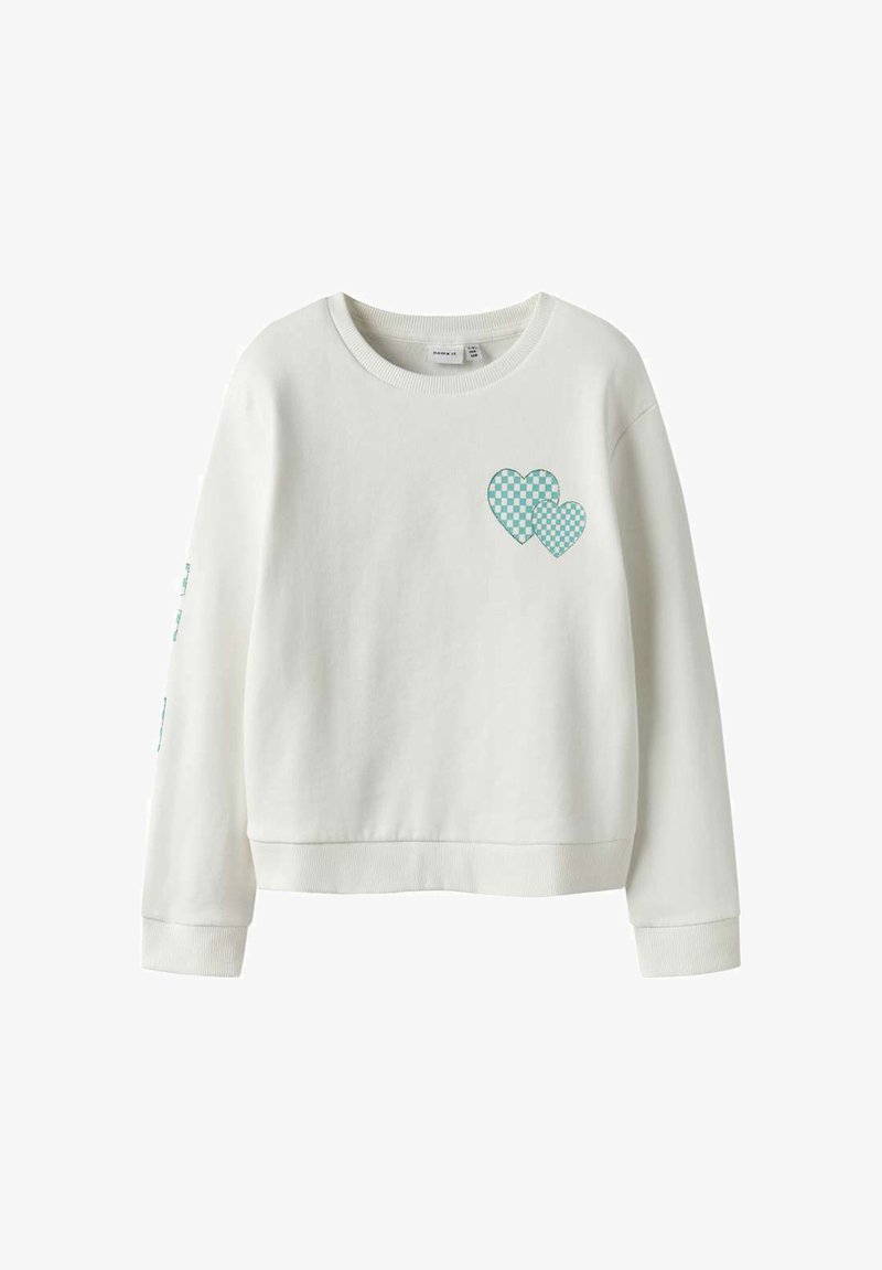 Sweatshirt blanc à manches longues avec un col rond, présentant deux petits cœurs à carreaux verts et blancs sur le haut gauche de la poitrine.