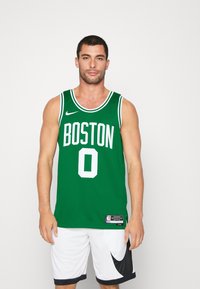 Zelena košarkaška majica Boston Celtics s bijelim slovima, brojem 0 i Nike logom. Nosi se s bijelim kratkim hlačama s crnim detaljem.