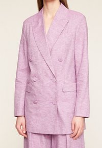 Dvouřadé sako ze světle levandulové látky. Má klopy s výřezem, dvě přední kapsy a texturovaný vzor tkaniny. Střižené na míru.