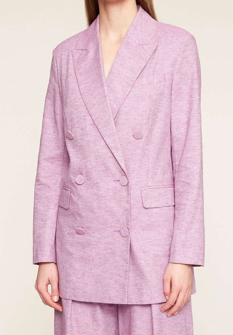 Dvouřadé sako ze světle levandulové látky. Má klopy s výřezem, dvě přední kapsy a texturovaný vzor tkaniny. Střižené na míru.