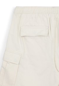 Pantalons cargo beige clair en coton, avec une taille élastique, des poches latérales et une poche arrière en patch pour un usage pratique.
