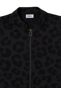 Veste zippée noire avec un motif en léopard texturé, dotée d'un col montant et d'une fermeture éclair en métal, étiquetée "CECIL."